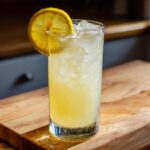 A tall, chilled glass filled with homemade lemonade and ice, garnished with a fresh lemon slice.