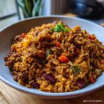 A close-up of a bowl filled with savory vegan dirty rice, featuring rice, beans, vegetables, and plant-based crumble.