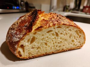 Cross-section of homemade bread showing a beautiful open crumb structure and dark, crispy crust.