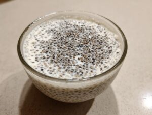 Close-up view of creamy coconut chia pudding in a glass bowl, topped with visible chia seeds.