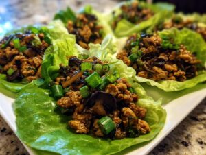 Close-up of several delicious chicken lettuce wraps filled with savory ground chicken and mushrooms, topped with green onions.