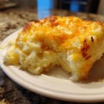Close-up of a serving of baked mashed potatoes topped with melted, golden cheddar cheese.