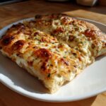 Close-up of two slices of delicious white pizza topped with melted, browned cheese and green herbs.
