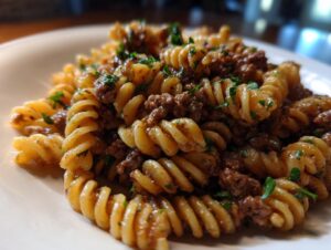 Close-up of creamy beef pasta featuring rotini or fusilli noodles mixed with ground beef sauce and fresh parsley.