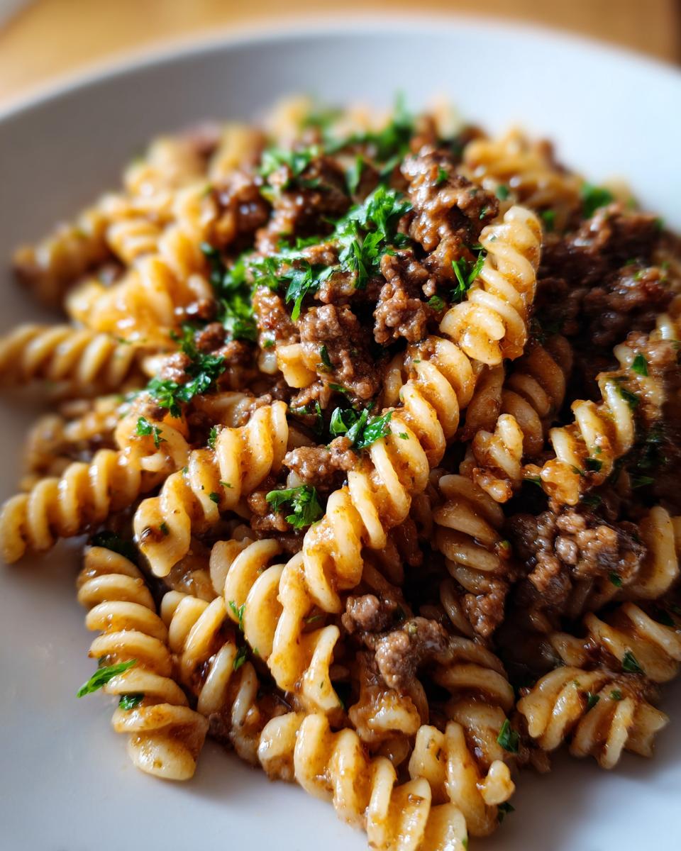 Close-up of creamy beef pasta made with fusilli noodles, topped with ground beef sauce and fresh parsley.