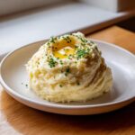 A mound of creamy garlic mashed potatoes topped with melted butter and fresh chives.