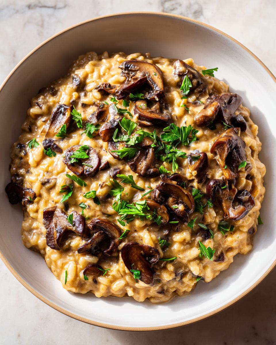Close-up of a creamy, savory dish, likely a risotto or stew, topped with sautéed mushrooms and fresh parsley, resembling white bean mushroom stew.