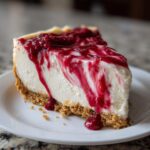 A perfect slice of creamy raspberry cheesecake topped with a rich, drizzled raspberry sauce.