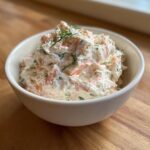 A white bowl filled with creamy smoked salmon dip, garnished with fresh dill.