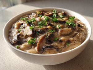A close-up of a creamy white bean mushroom stew topped with fresh parsley in a white bowl.