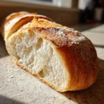 Close-up of the airy, white interior (crumb) of a freshly baked French bread loaf dusted with flour.