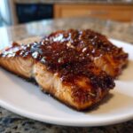 Two pieces of perfectly cooked salmon topped with a thick, dark, sweet and savory glaze.