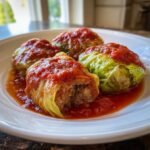 Four savory cabbage rolls stuffed with filling and topped with rich tomato sauce, ready to eat.