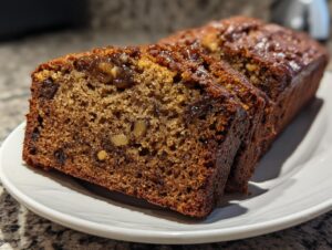 Close-up of moist date nut bread slices showing visible dates and walnuts in the rich brown crumb.
