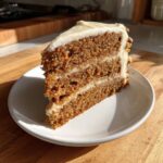 Close-up of a thick, moist slice of spice cake with two layers of cream cheese frosting.