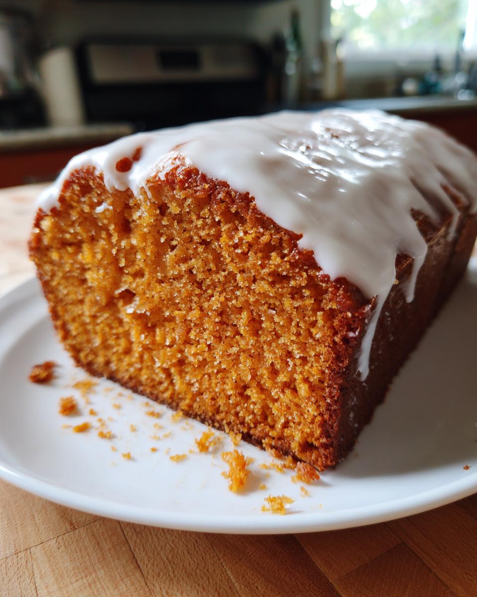 Close-up of a slice of moist sweet potato pound cake topped with a thick white glaze.