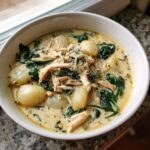 A close-up of creamy Olive Garden Chicken Gnocchi Soup featuring shredded chicken, potato gnocchi, and wilted spinach.