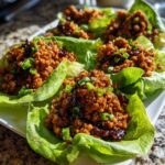 Close-up of several delicious chicken lettuce wraps filled with savory, saucy ground chicken and topped with green onions.