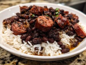 Close-up of a bowl of savory black beans and rice topped with thick slices of smoked sausage.