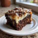 A moist slice of german chocolate poke cake with white filling and pecan caramel topping on a white plate.
