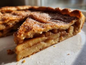 Close-up of a slice of homemade apple galette showing the cinnamon-spiced apple filling and a sugary, flaky crust.