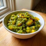 Close-up of a white bowl filled with chunky, vibrant green tomato salsa, featuring visible pieces of roasted yellow/green tomato.