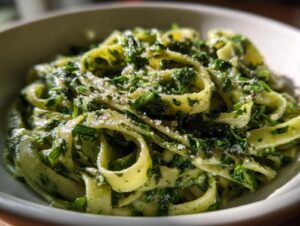 A close-up shot of creamy, vibrant green spinach pasta noodles tossed in a rich sauce and topped with grated cheese.