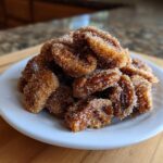 A close-up of a small white plate piled high with glistening candied pecans recipe nuts coated in sugar.