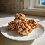 A stack of gooey, caramel-coated avalanche cookies featuring white chocolate chips on a white plate.