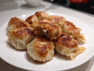 A plate of golden-brown, pan-fried rice paper dumplings showing crisp bottoms and soft tops.