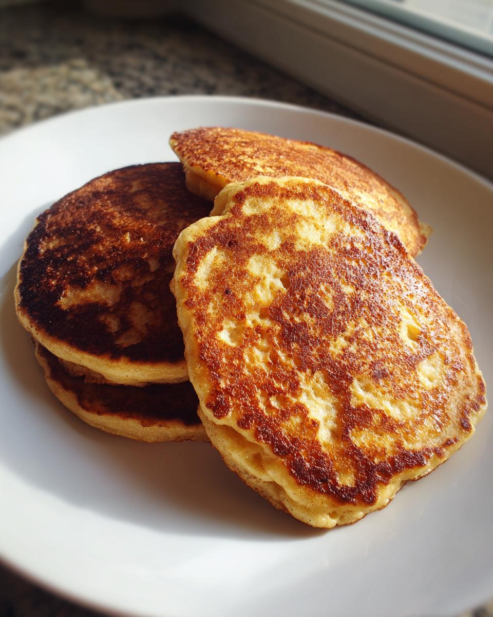 Close-up of a stack of golden-brown banana oatmeal pancakes on a white plate.