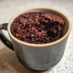 Close-up of a rich, dark chocolate mug cake with visible chocolate chips, ready to eat.