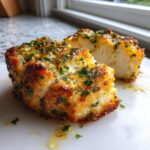 Close-up of a juicy baked chicken breast, sliced in half, showing white meat and a golden, herbed crust.