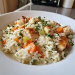 Close-up of a serving of one pot chicken and rice with visible chunks of seared chicken, carrots, and celery, topped with parsley.