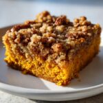 A moist slice of bright orange pumpkin crunch cake topped with a thick, sugary pecan streusel.