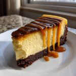 A decadent slice of salted caramel cheesecake with a thick brownie crust and rich caramel drizzle.