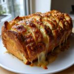 A golden brown, baked loaf of amazing 1-step cheese bread, sliced and oozing melted cheese.