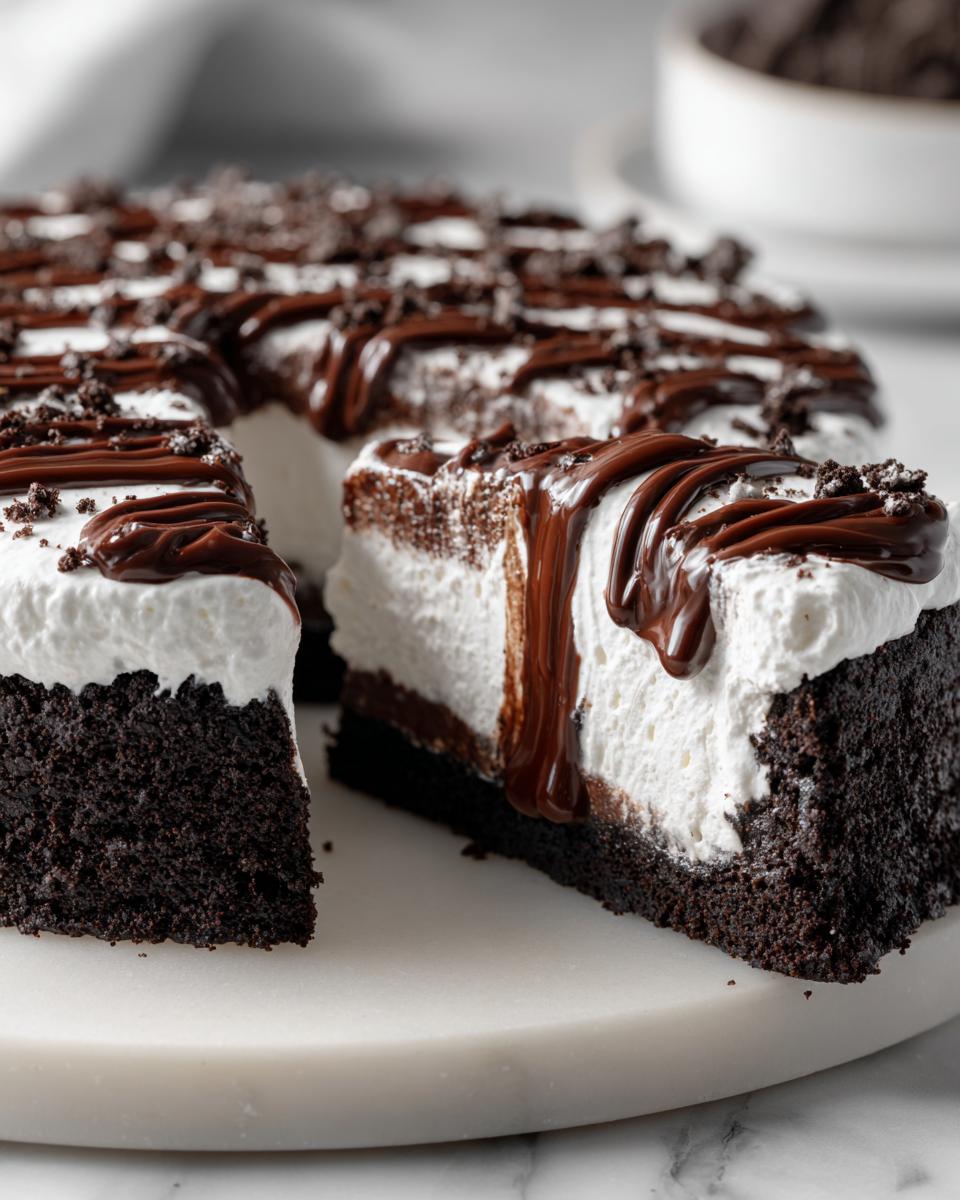 A close-up of a rich chocolate ice cream pie slice showing a dark crust, thick white filling, and chocolate fudge drizzle.