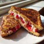 Two halves of golden brown stuffed french toast filled with cream cheese and fresh strawberries.