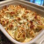 Close-up of baked chicken alfredo stuffed shells covered in melted, golden-brown cheese and parsley.