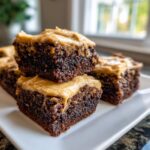 Close-up of stacked, fudgy banana bread brownies topped with thick peanut butter frosting.