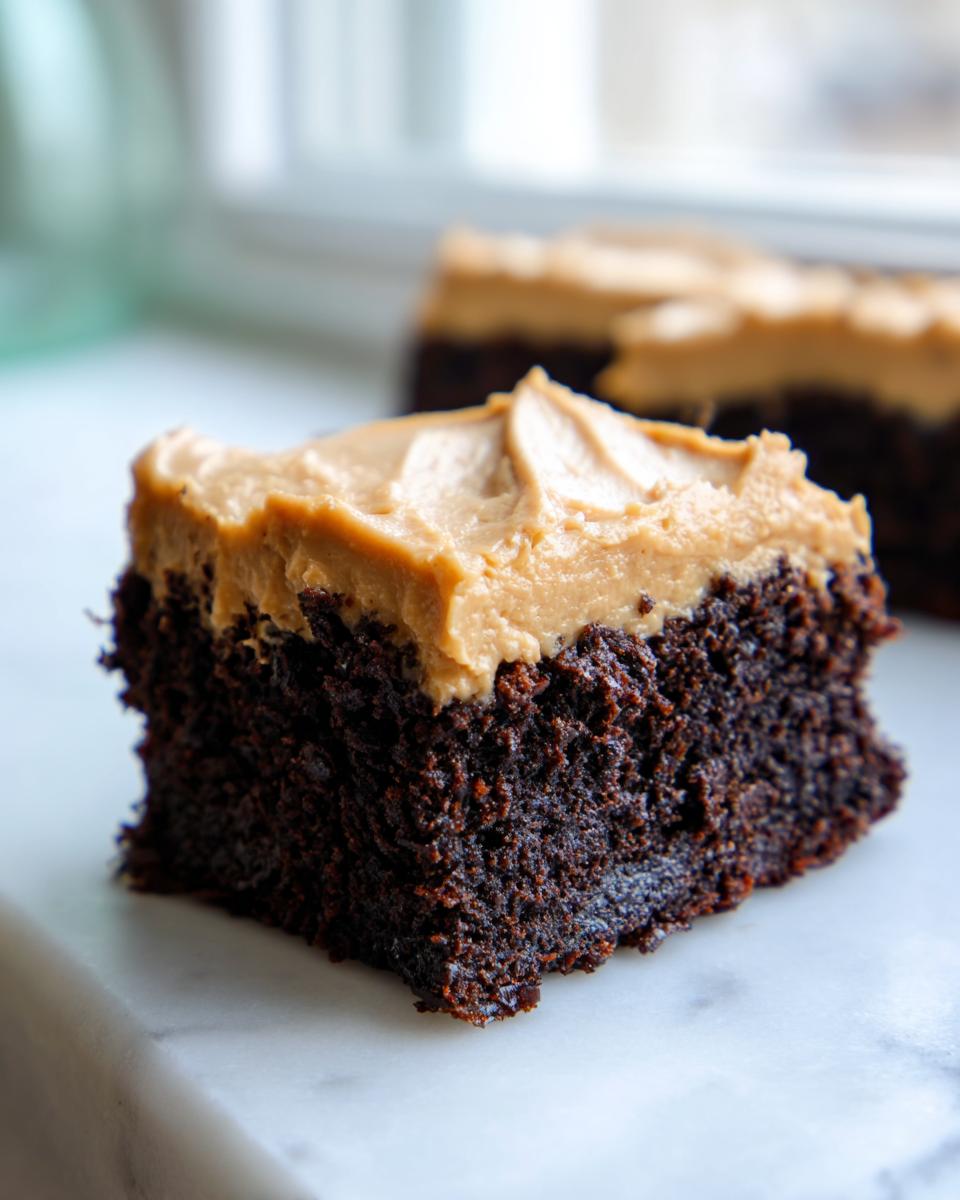 Close-up of a rich, dark chocolate banana bread brownies square topped with thick peanut butter frosting.