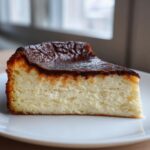 A perfect slice of Basque burnt cheesecake showing the creamy interior and dark caramelized top.
