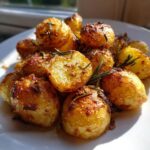 A close-up of golden brown, crispy roast potatoes seasoned with rosemary and garlic.