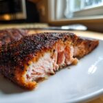 Close-up of a perfectly cooked piece of blackened salmon showing its flaky, moist interior.
