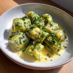 Close-up of tender braised leeks cut into pieces, served in a creamy sauce and topped with fresh parsley.