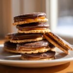 A tall stack of homemade Caramel Ritz Cracker Christmas Cookies layered with gooey caramel and dipped in dark chocolate.