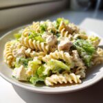 Close-up of a creamy chicken caesar pasta salad featuring fusilli pasta, diced chicken, and crisp romaine lettuce.