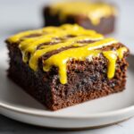 Close-up of a fudgy chocolate Lemon Brownies square topped with bright yellow lemon glaze drizzle.