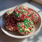 A stack of round Christmas sprinkle sugar cookies covered in red, green, and white nonpareils.